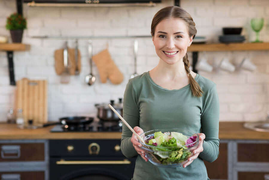 Woman in her kitchen using Jake's Jake's StrongGinger organic ginger juice in her salad dressing.