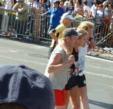 Mike Dooley, a Jake's StrongGinger organic ginger juice customer helping woman cross line at Boston Marathon
