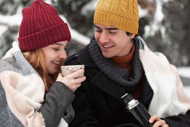 A romantic couple outside in the snow sharing a cup of Jake's StrongGinger organic ginger juice