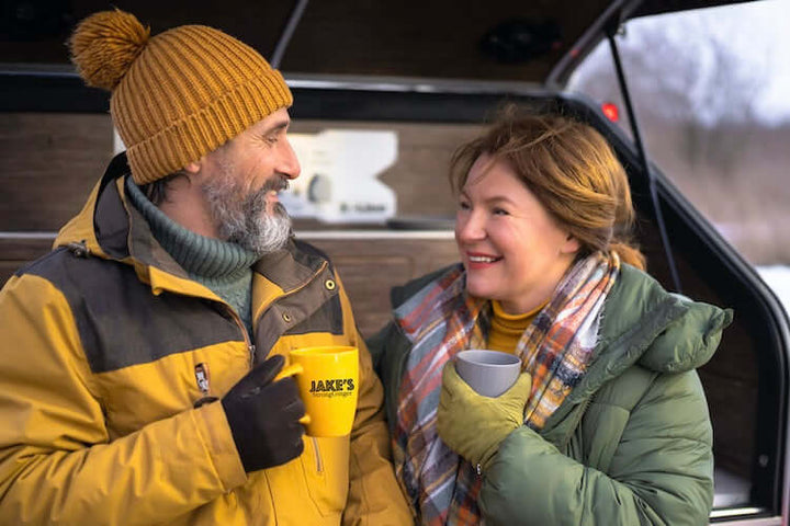 An older couple in the backend of a care drinking hot Jake's StrongGinger organic ginger juice after skiing or snowshoeing