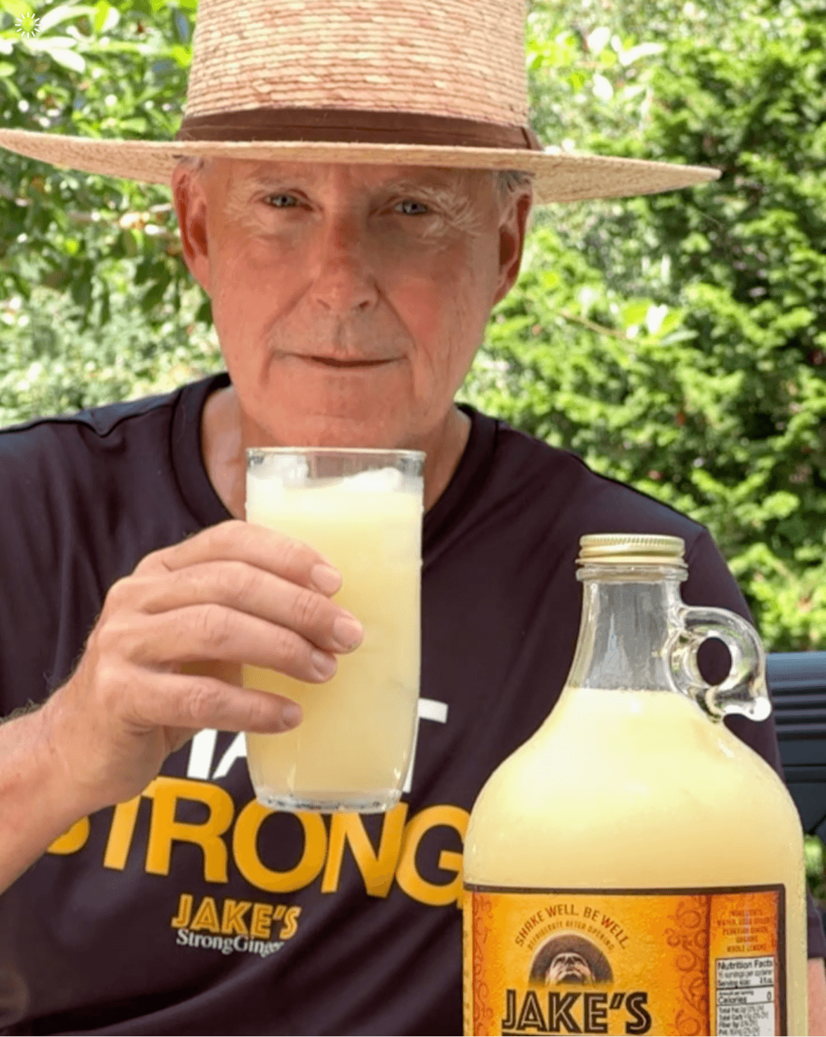 A picture of Jake in his black shirt and straw hat drinking a glass of Jake's StrongGinger organic ginger juice