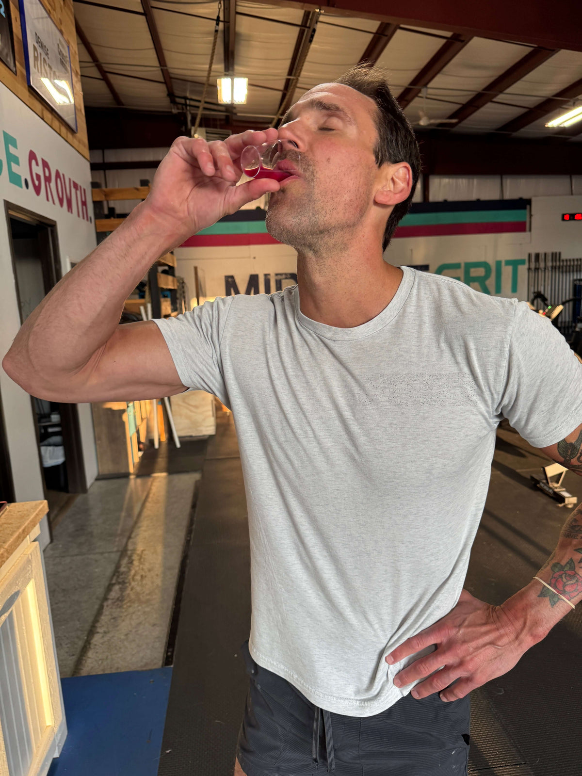 A Crossfit athlete drinking a shot of Jake's StrongGinger organic pomegranate ginger juice 